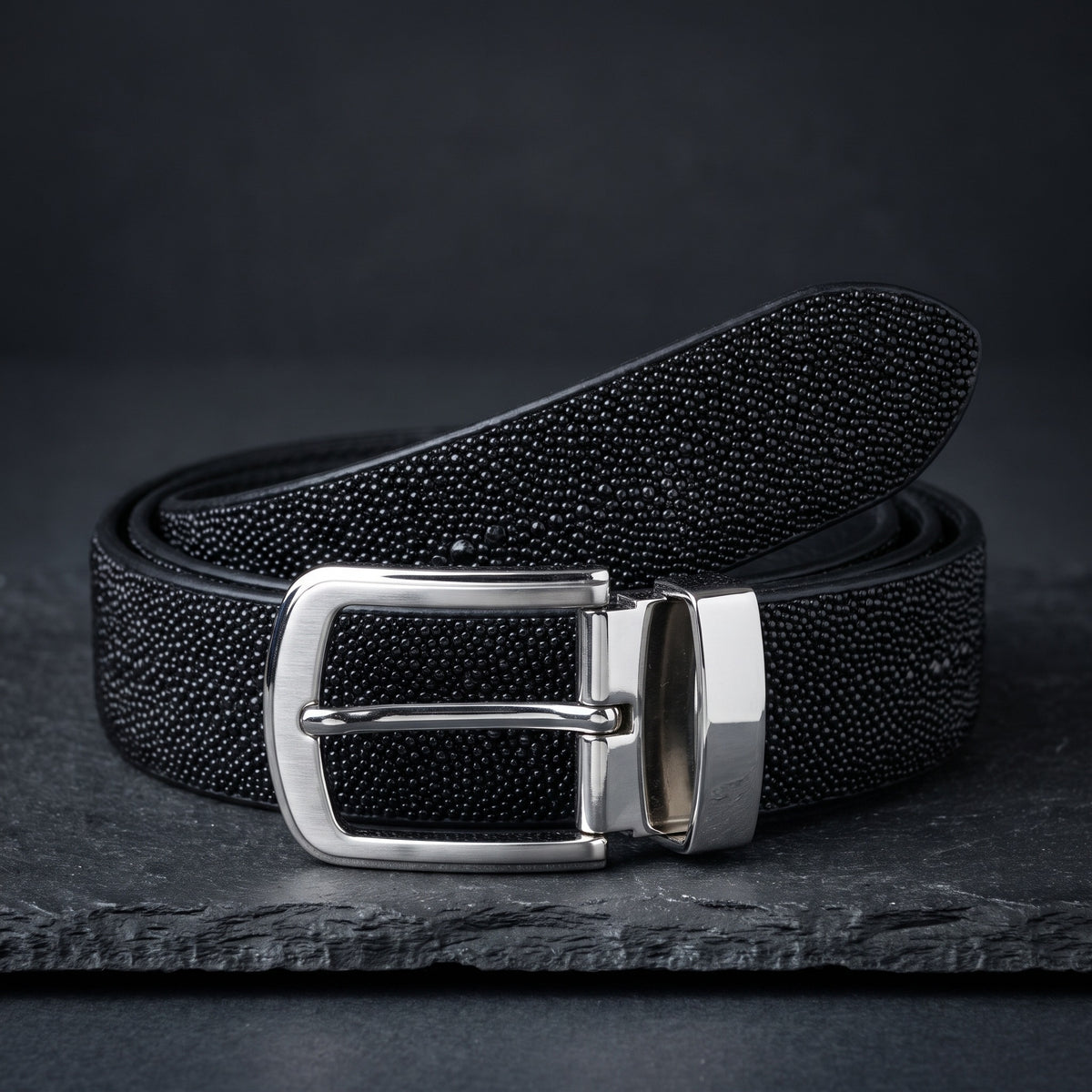 Black Stingray Belt, rolled, on dark slate