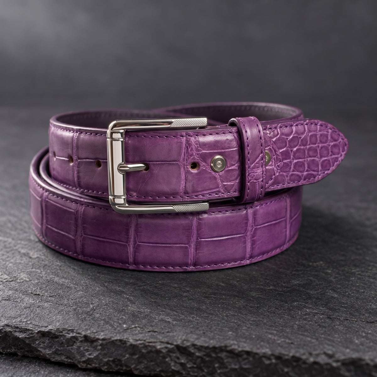 Purple Crocodile Belly Belt, rolled, on dark slate