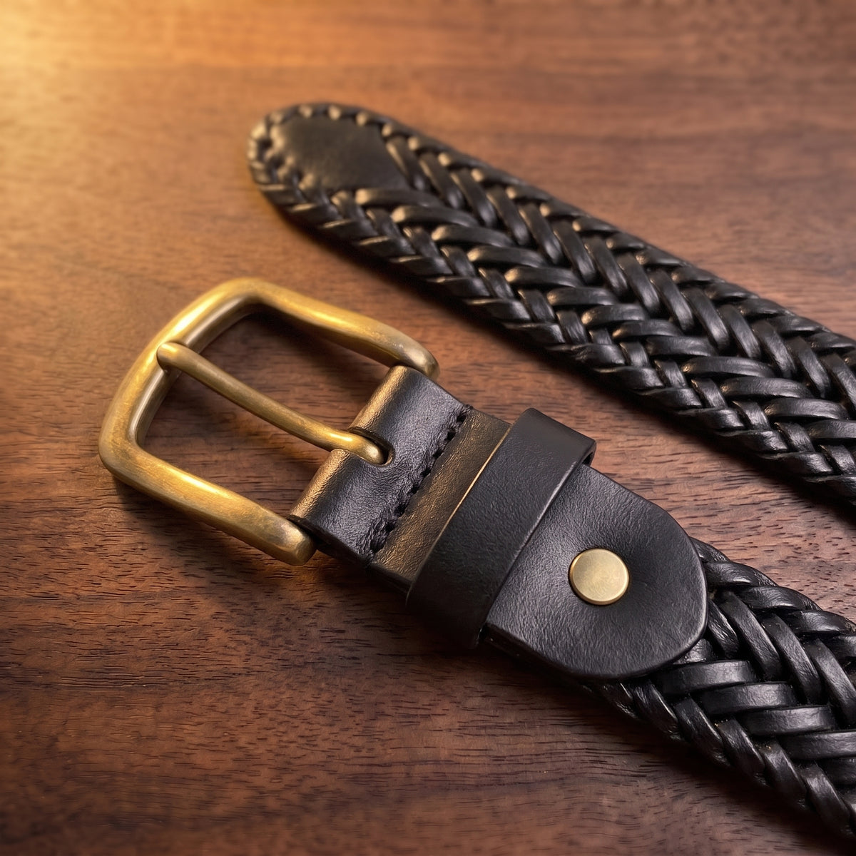 The Braided Leather Belt in Black, close-up of the buckle end [Black]