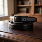 The Italian Dress Belt in Black, on a walnut executive desk [Black]