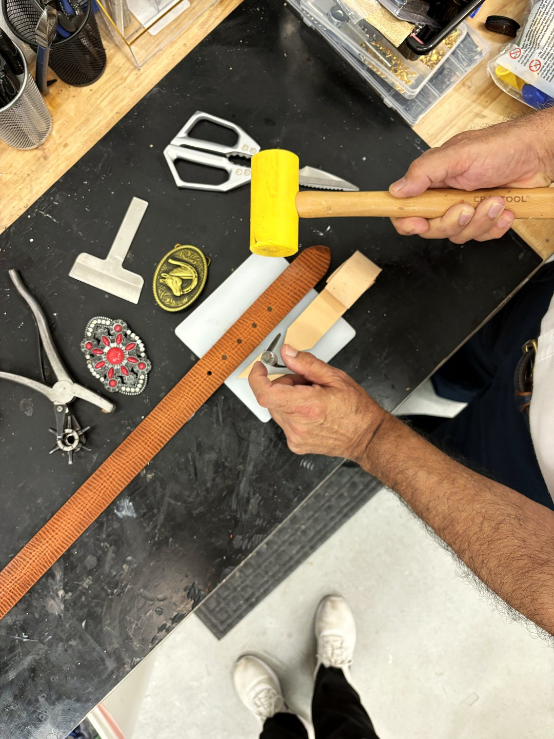 The bench: cutting a strap with the mallet, buckles and tools around it